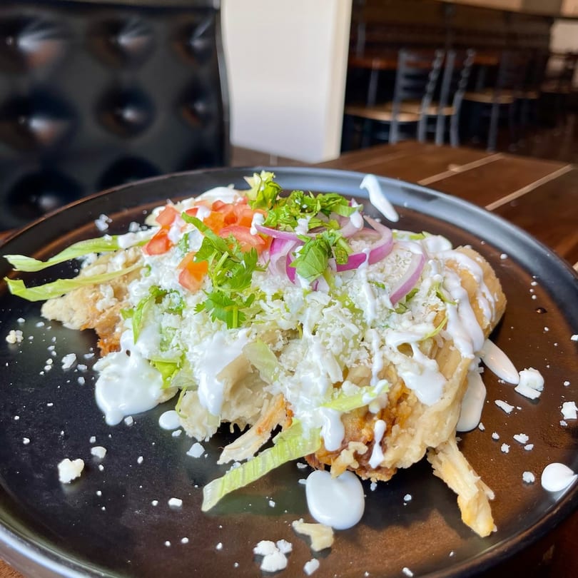 Condesa Tacos & Tequila's Mexican dish with shredded chicken, lettuce, tomato, onion, cheese, and crema.
